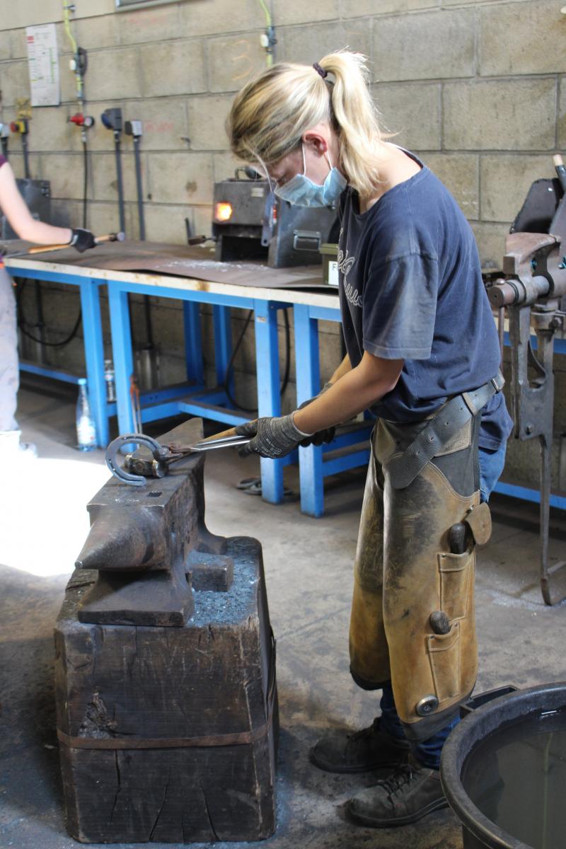 Célestine à la forge : des mouvements précis pour adapter la forme du fer en le faisant chauffer et en le martelant.